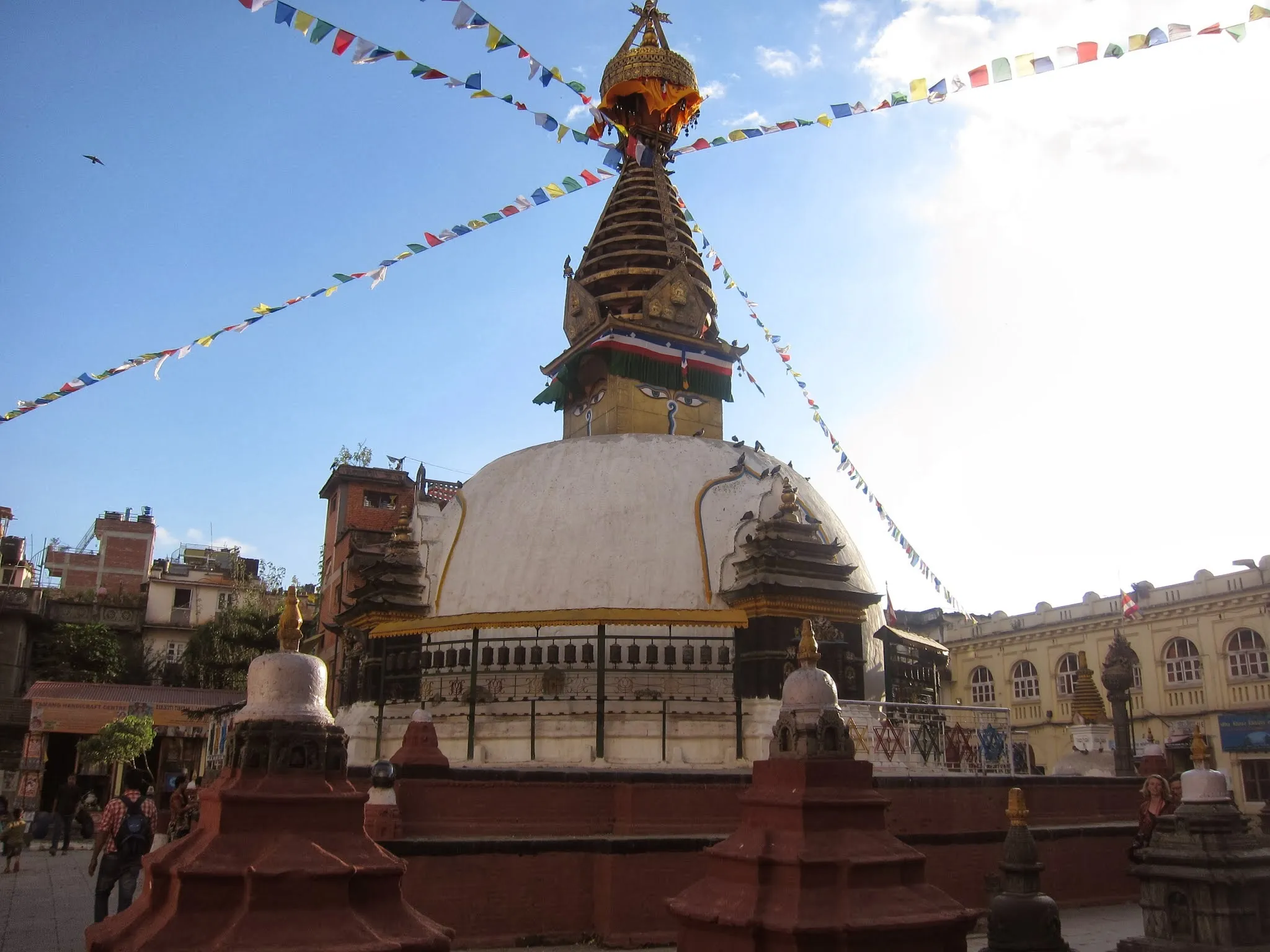 Buddyjska stupa zwieńczona złotą iglicą, z powiewającymi chorągiewkami modlitewnymi.